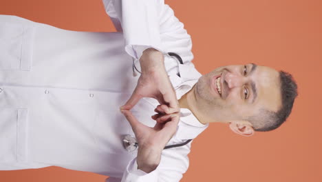 Vertical-video-of-Doctor-making-heart-looking-at-camera.